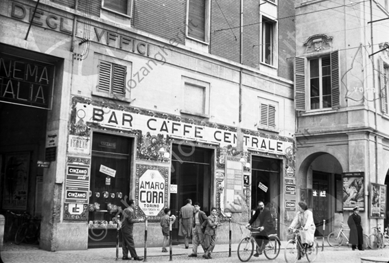 Facciata del Bar Centrale di Cesena Bambini ragazzi o persone in bicicletta vigile manifesti del cinema Italia amaro Cora Cinzano ingresso corte Dandini noleggio auto