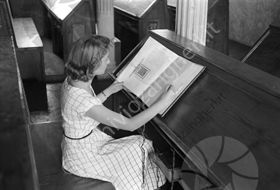 Modella tra i banchi nell'aula del Nuti Biblioteca Malatestiana Ragazza leggere sfogliare volume incunaboli codice panche di legno