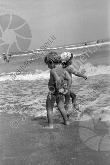 bambini a riva bimbo tira su il costumino onde bagno riva mare