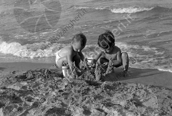 bimbi che giocano con la sabbia a riva mare onde 