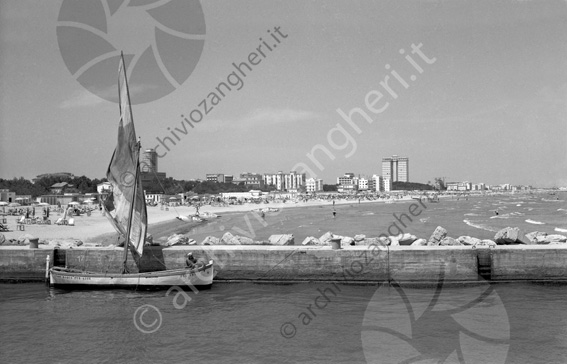 barca nel canale con veduta di Milano Marittima barca per gite grattacieli mare riva spiaggia pietre scogli ombrellone sdraio pattino bagnanti costa riviera panoramica scalette bitta 