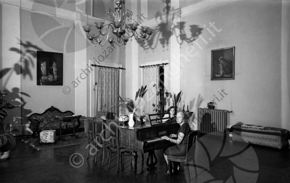 Palazzo Tonti (via Manfredi) salone salone pianoforte sedie quadro lampadario divano termosifone radiatore tende cassapanca vaso fiori tappeto signora