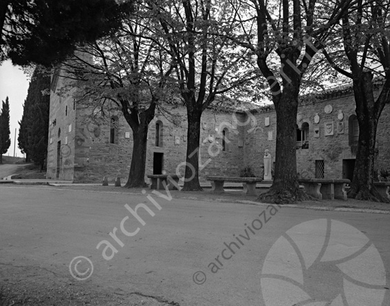 Chiesa Pieve di San Donato di Polenta esterno con giardino chiesa laterale giardino alberi piazzetta panchine stemmi e statua del Carducci alberi
