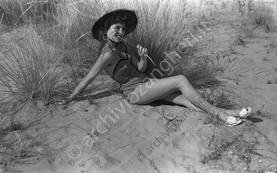 Ragazza in spiaggia Ragazza in costume da bagno cappello sabbia filo d'erba