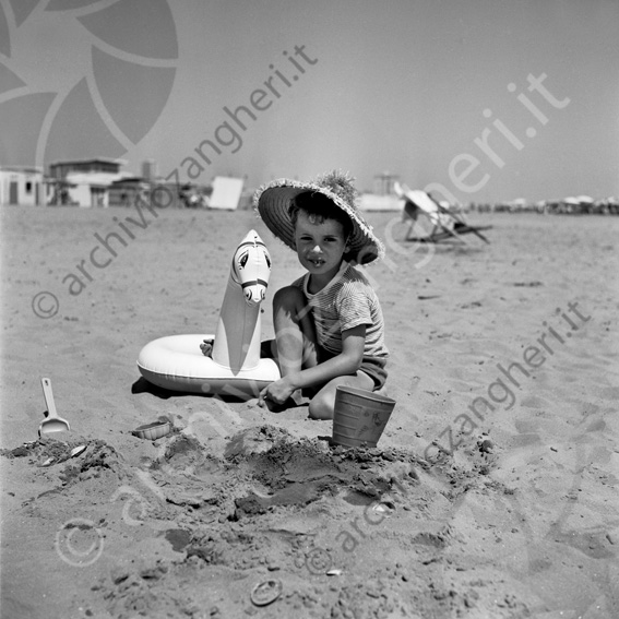 bambino con salvagente in spiaggia Ciambella cavallino paletta secchiello spiaggia sabbia