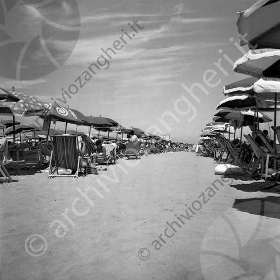 La spiaggia tra gli ombrelloni Fila corridoio ombrelloni sdrai estate spiaggia