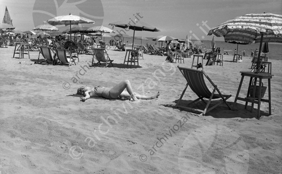 Ragazza in spiaggia e ombrelloni Ragazza stesa sulla sabbia sdraio ombrellone spiaggia mare estate