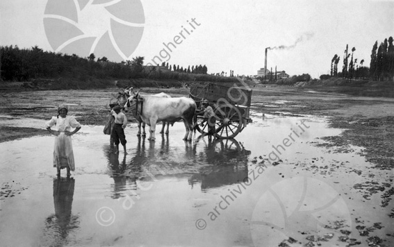 Contadini attraversano il fiume Savio con il carro trainato dai buoi Famiglia vuoi carro ciminiera fumo nero fabbrica fiume acqua argini