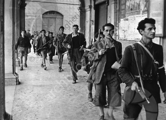 un gruppo di partigiani che attraversano i portici del palazzo OIR dopo la ritirata dei tedeschi nel 1944 Lastra vetro 9x12 neg + lastra vetro 9x12 pos Molto probabilmente un gruppo di partigiani che attraversano i portici del palazzo OIR dopo il passaggio degli inglesi nel 1944 Fucili camminare
